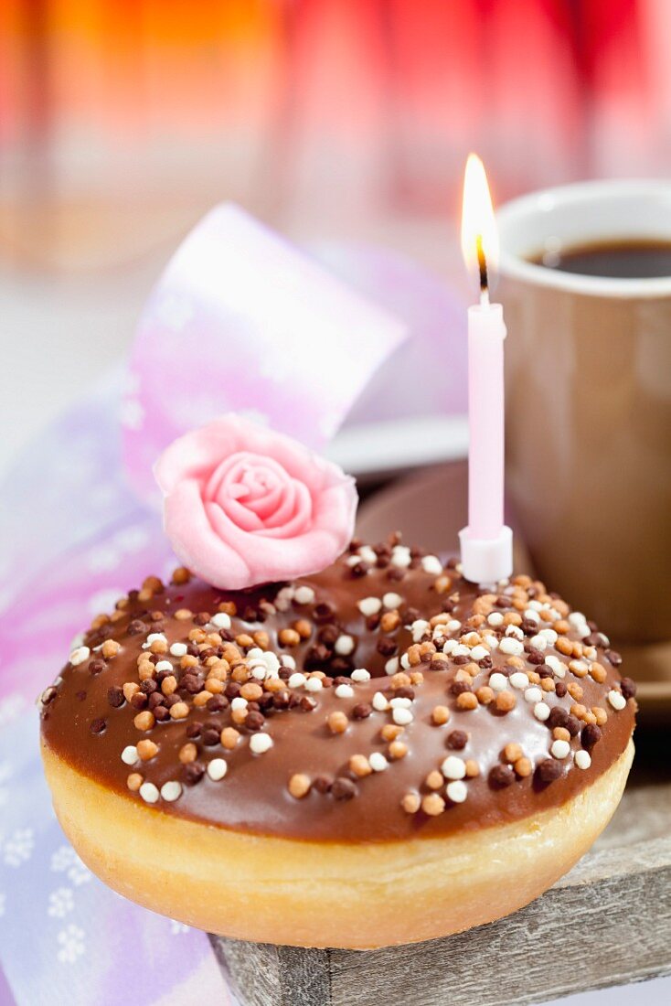 A doughnut with chocolate icing and a birthday candle