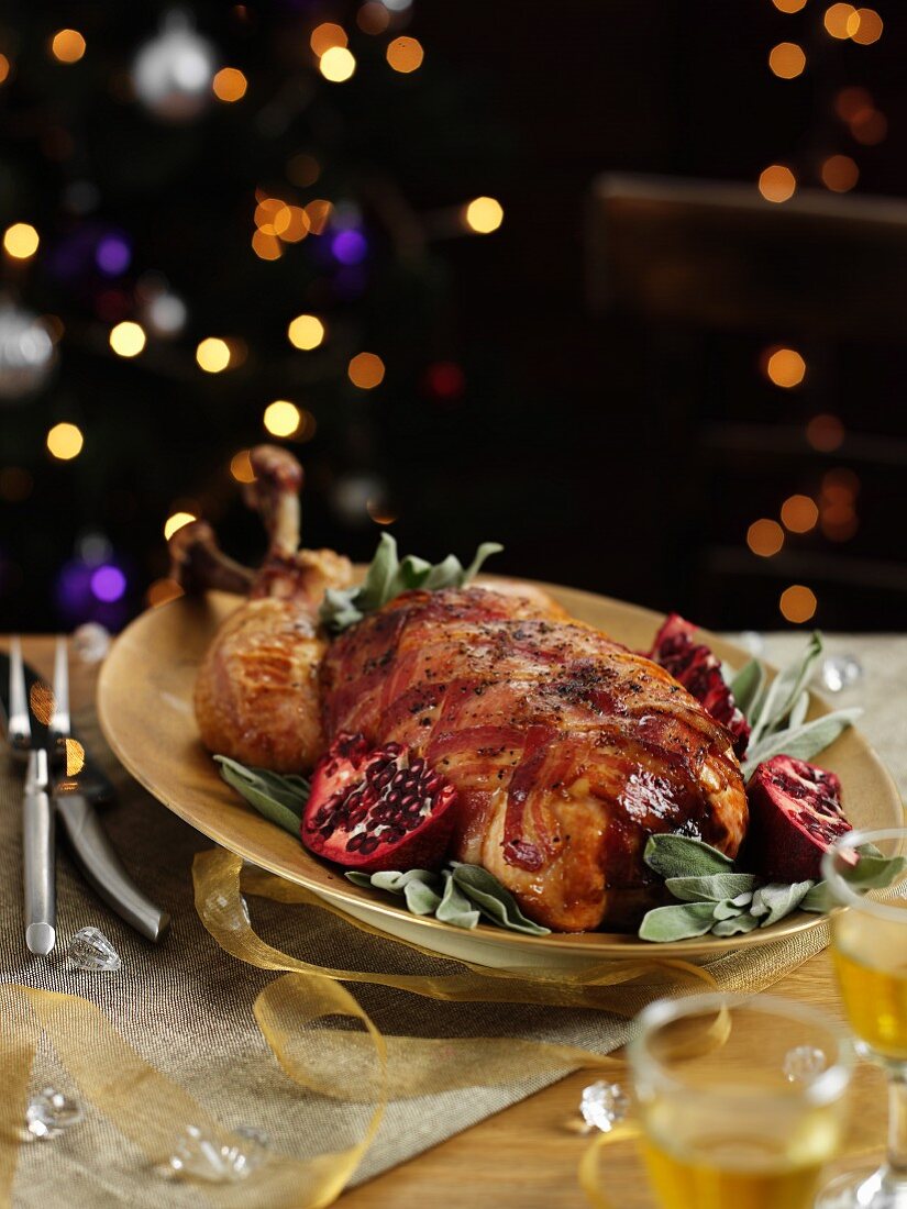 Roast turkey wrapped in bacon on sage with pomegranate seeds