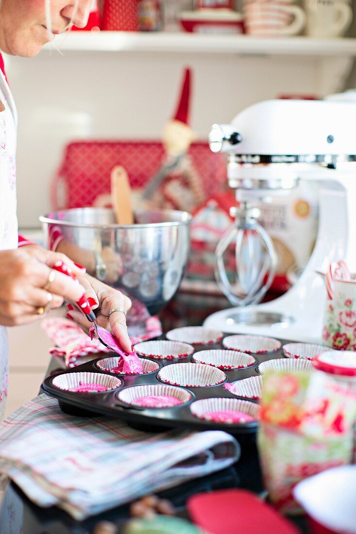 Cake mixture being transferred to muffin cases