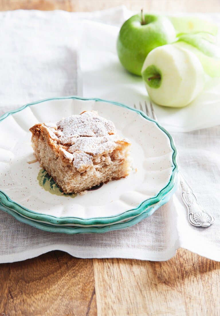 A slice of apple cake dusted with icing sugar