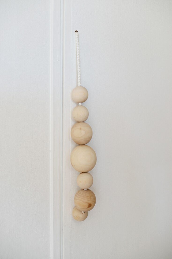 Wooden balls of different sizes threaded on cord as handle of cupboard door