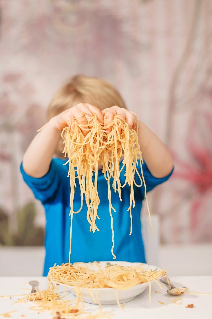 A boy holding spaghetti in his hands