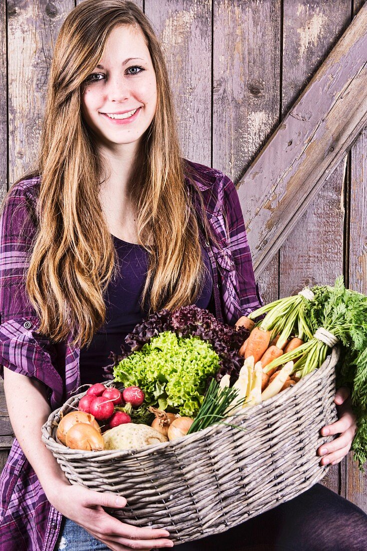 A girl holding a basket of fresh vegetables