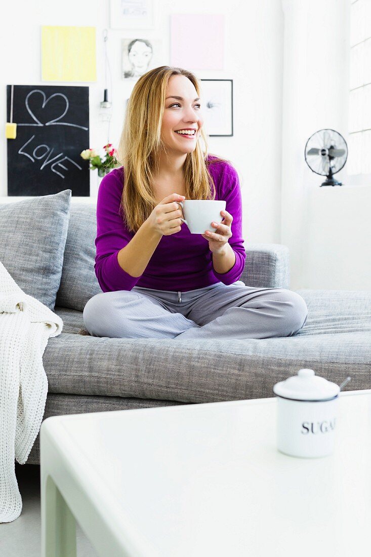 Frau mit Teetasse auf dem Sofa
