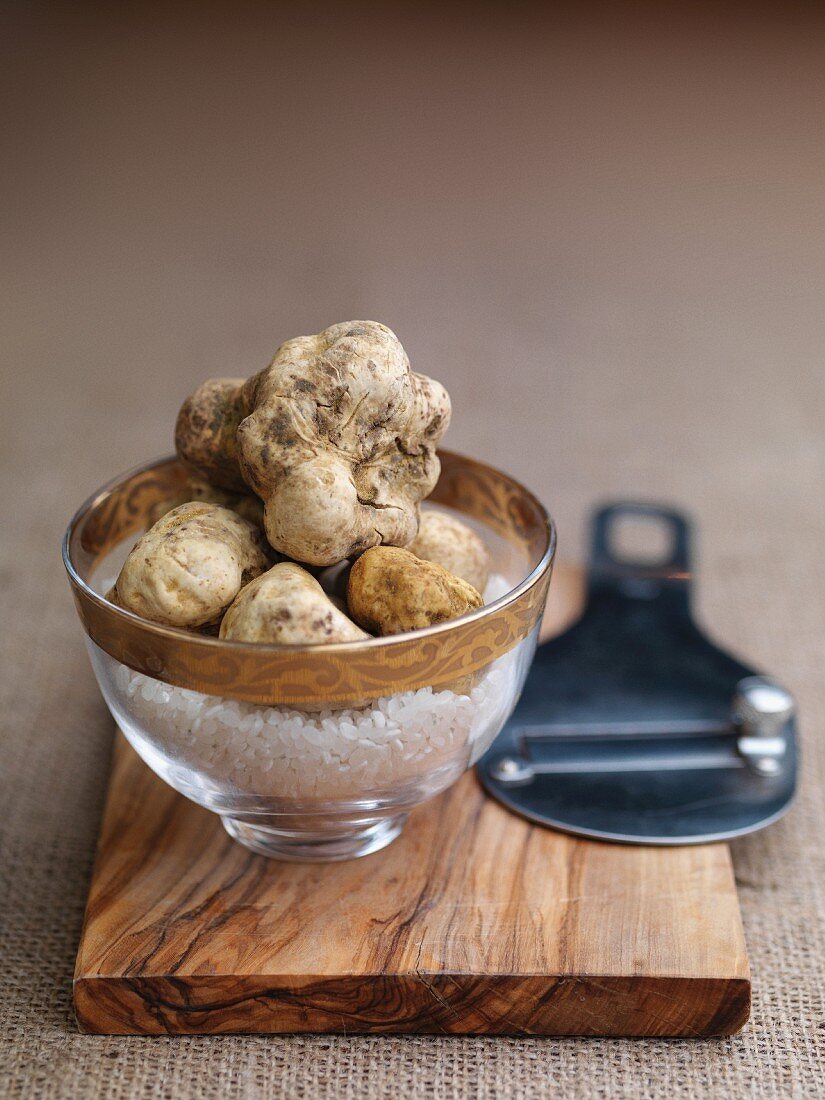 White truffles in a glass bowl on a wooden board