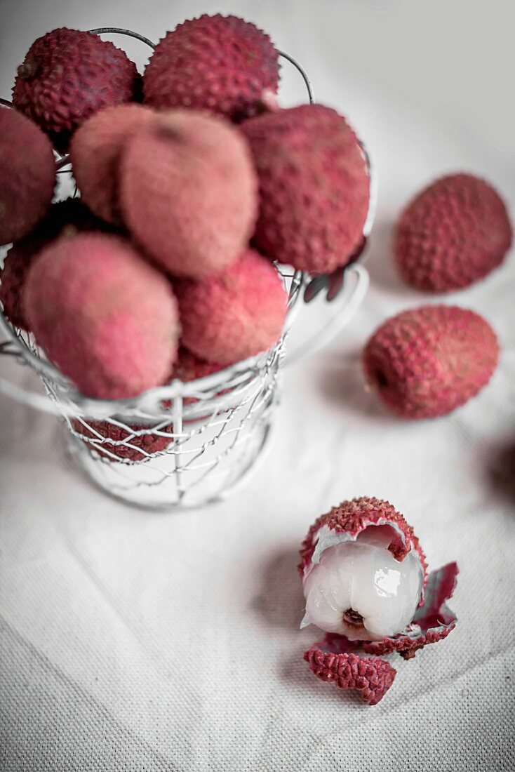 Mehrere Lychees, teilweise im Drahtkorb