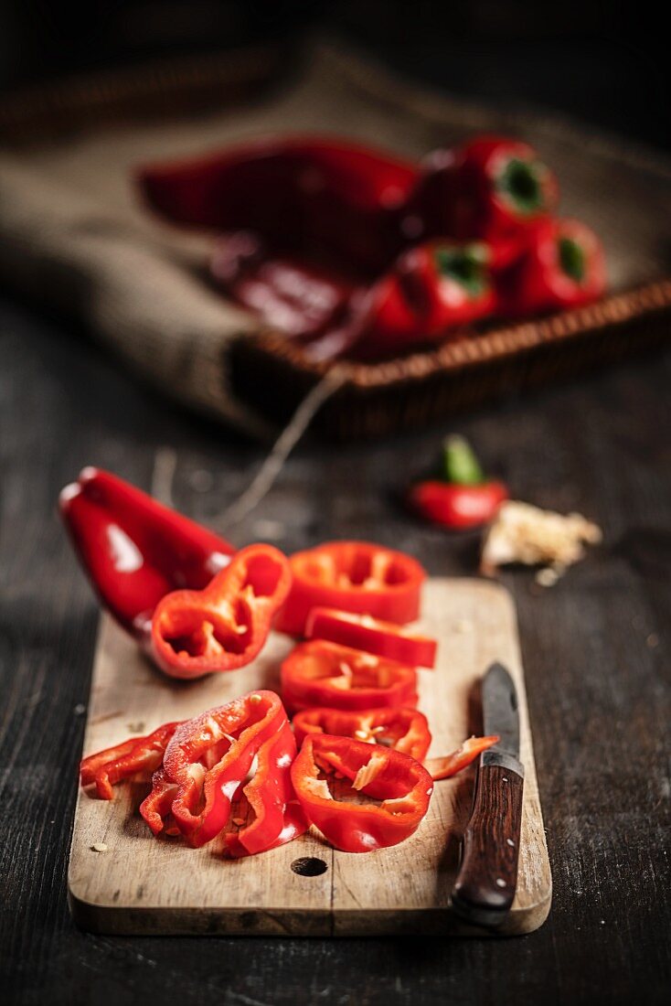Sliced red pointed peppers on a board with a knife