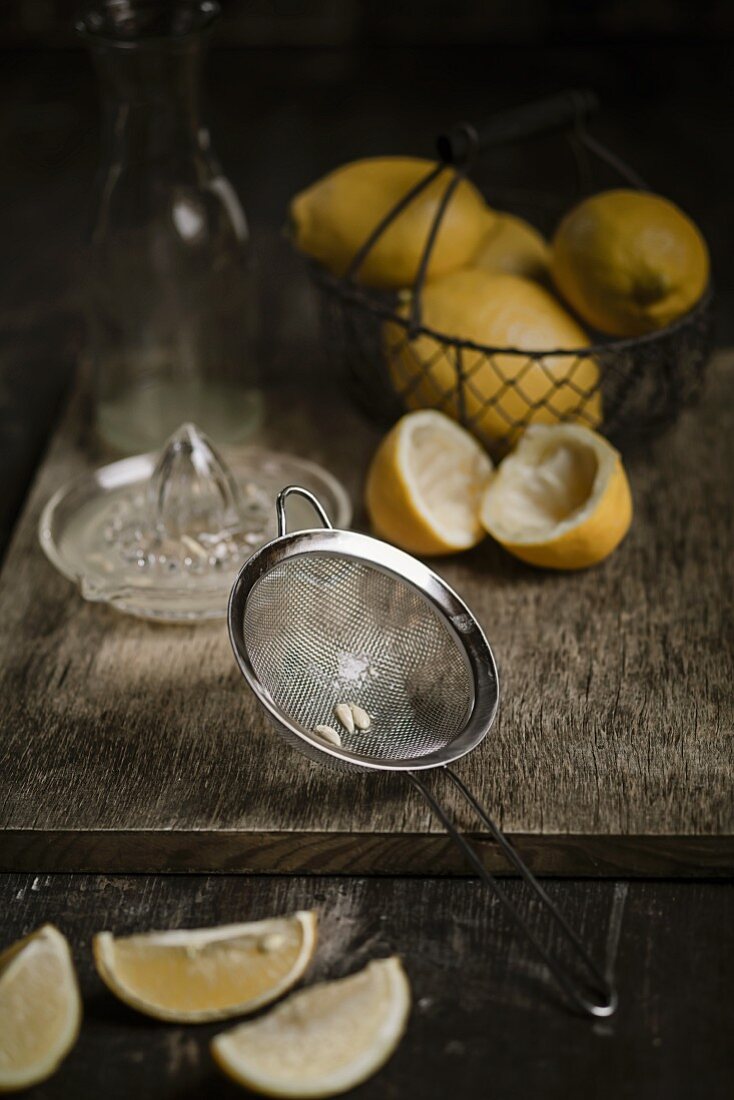 Lemon pips in a sieve and juiced and whole lemons