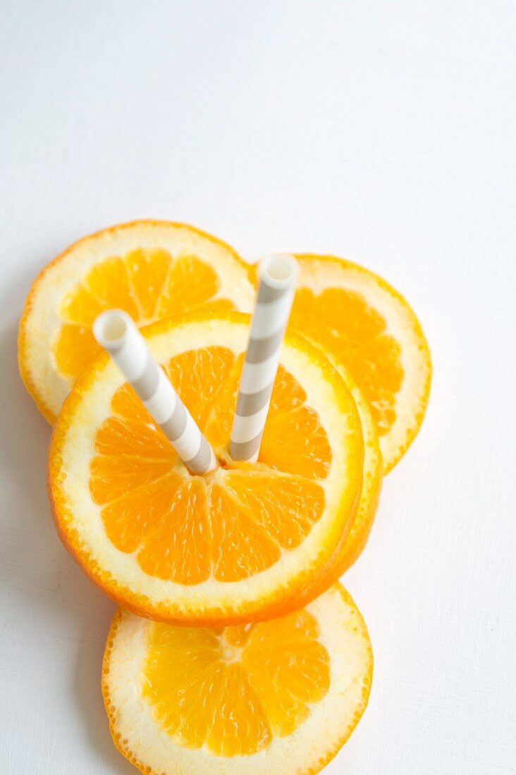 Orangenscheiben mit Strohhalmen (Draufsicht)