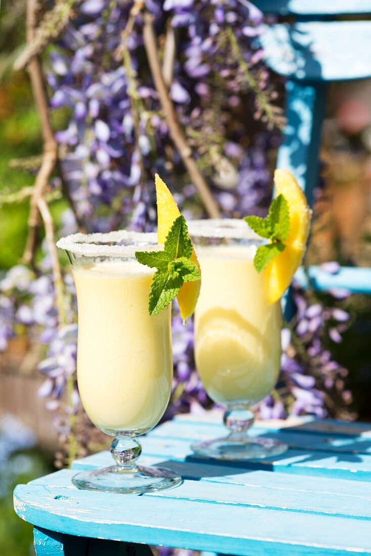 Two mango and buttermilk shakes on a garden table