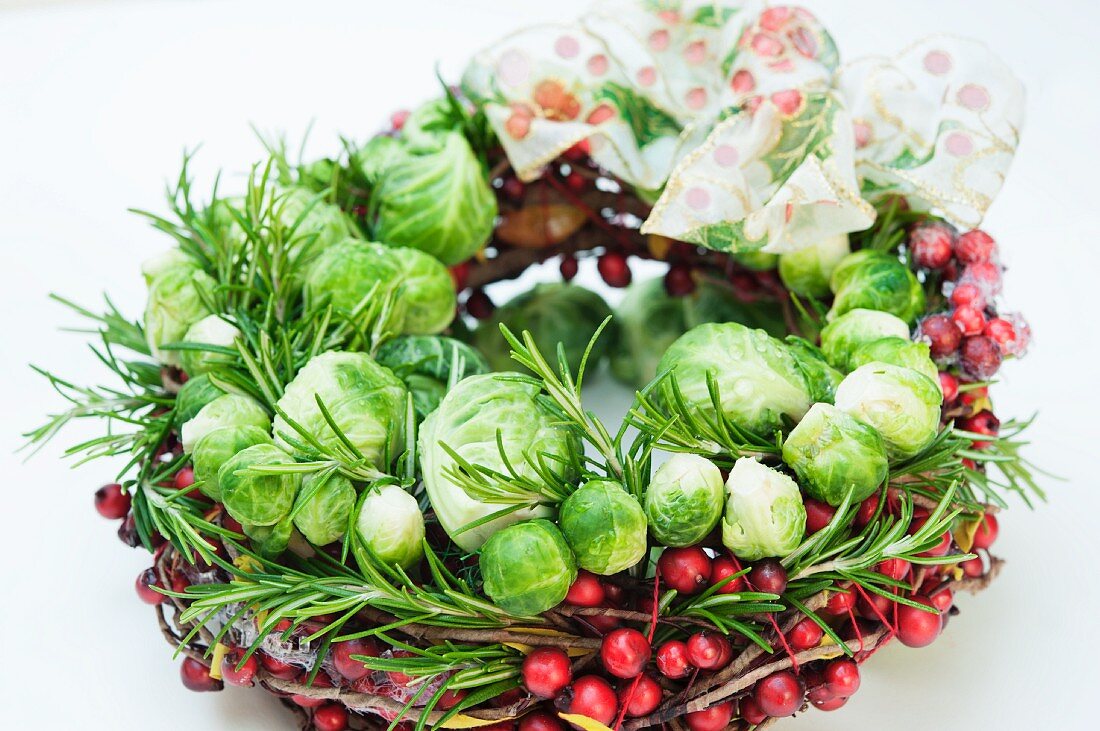 A Christmas wreath made of Brussels sprouts, cranberries and rosemary with a ribbon