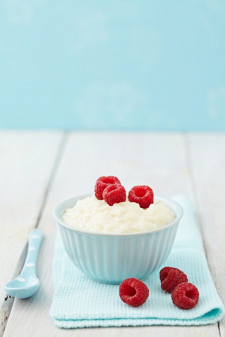 A bowl of rice pudding with raspberries