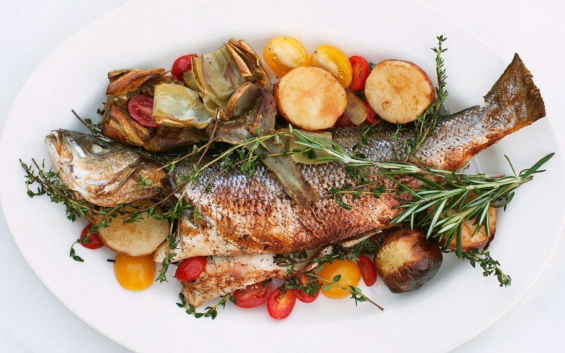 Grilled fish with herbs on a bed of Mediterranean vegetables