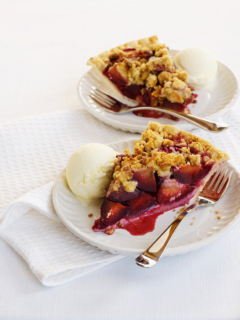 Two slices of plum crumble pie with vanilla ice cream