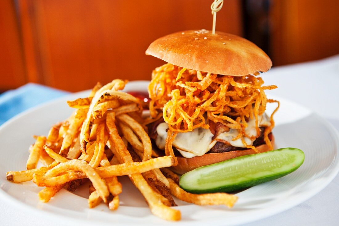 A cheeseburger with fried onions and chips