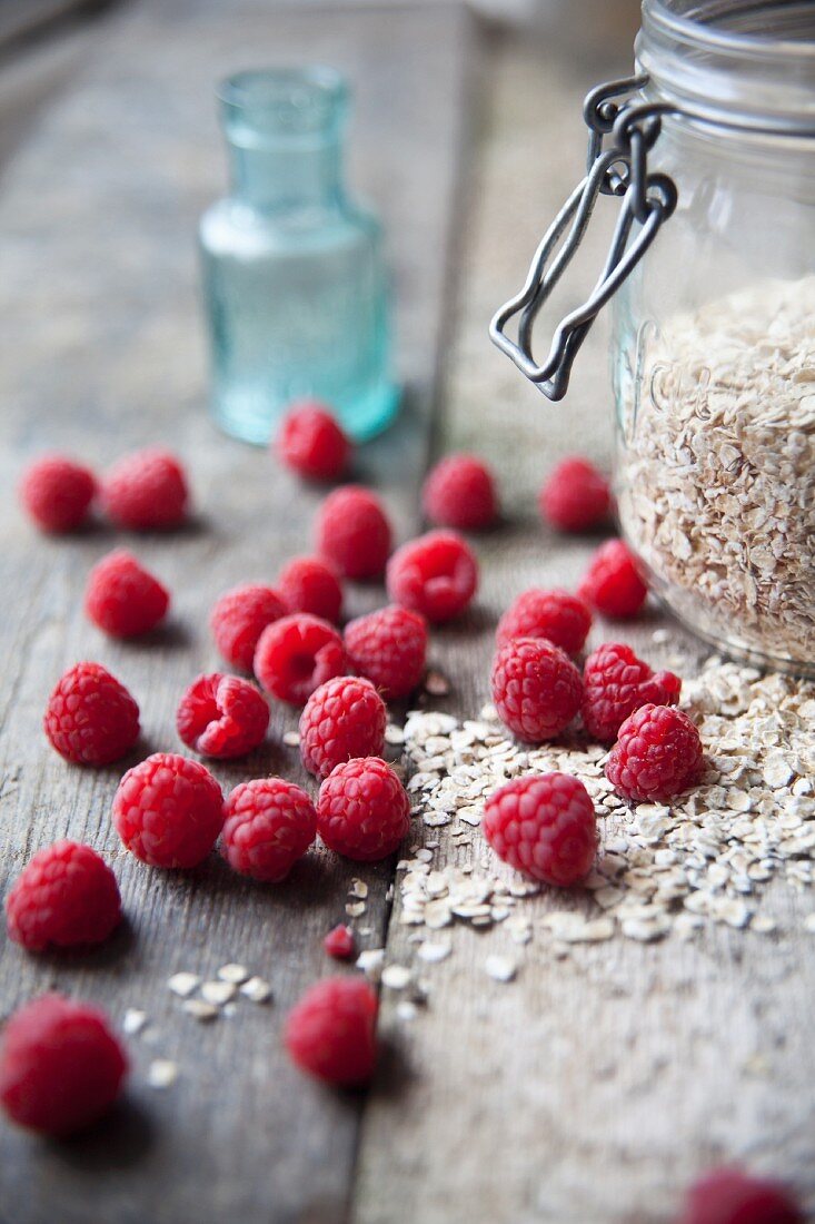 Fresh raspberries and a jar of oats on a wooden table