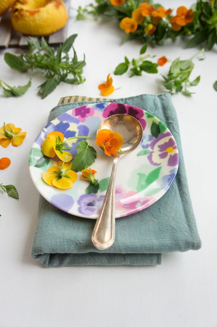 A place setting with tufted pansies and a spoon