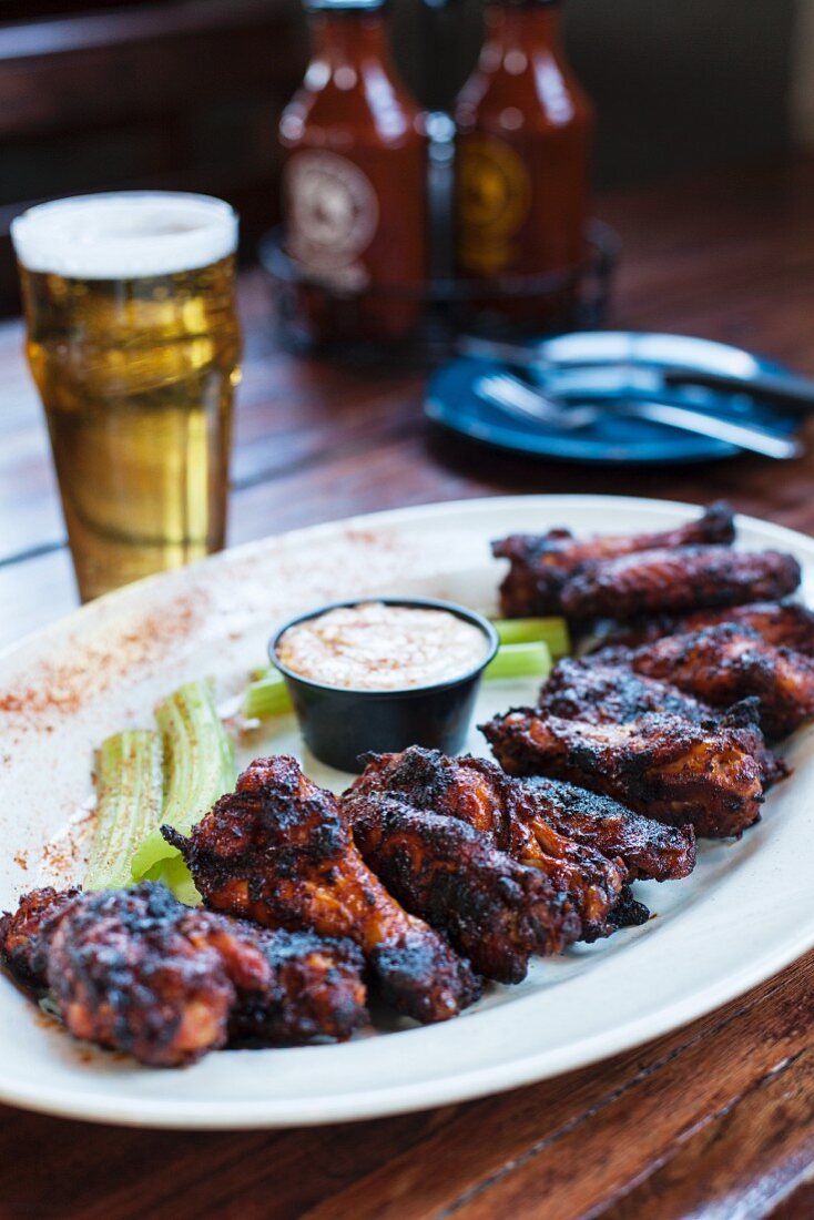Grilled chicken wings with celery, dip and a glass of beer