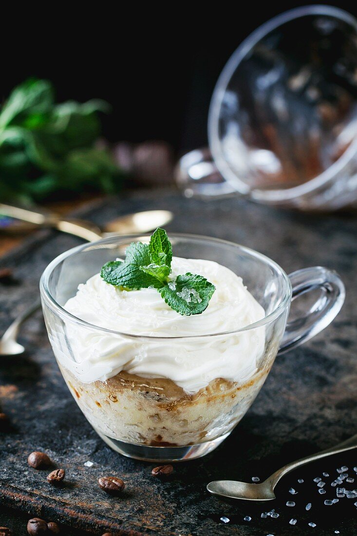 Sponge cake with cream, coffee and fresh mint in a glass cup