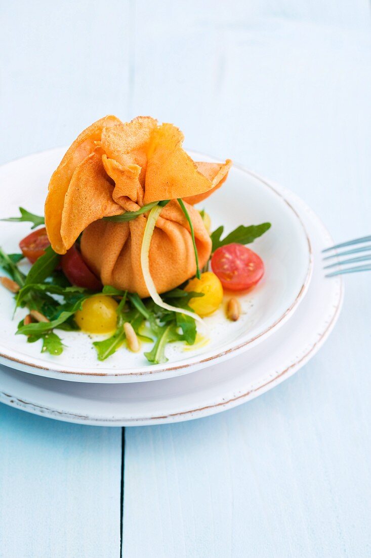 Gefülltes Crepesäckchen auf Rucola-Tomatensalat