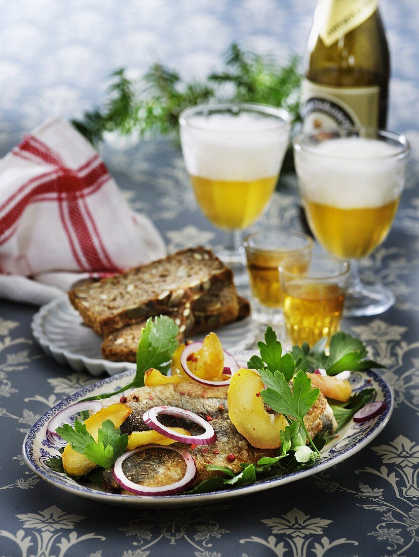 Fried herring with apples and onions served with Aquavit and beer (Scandinavia)