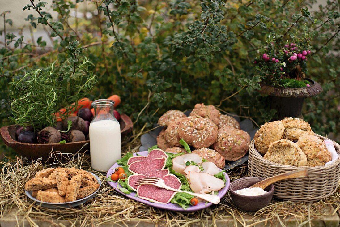 An autumnal buffet with rolls, sausages and vegetables in a garden
