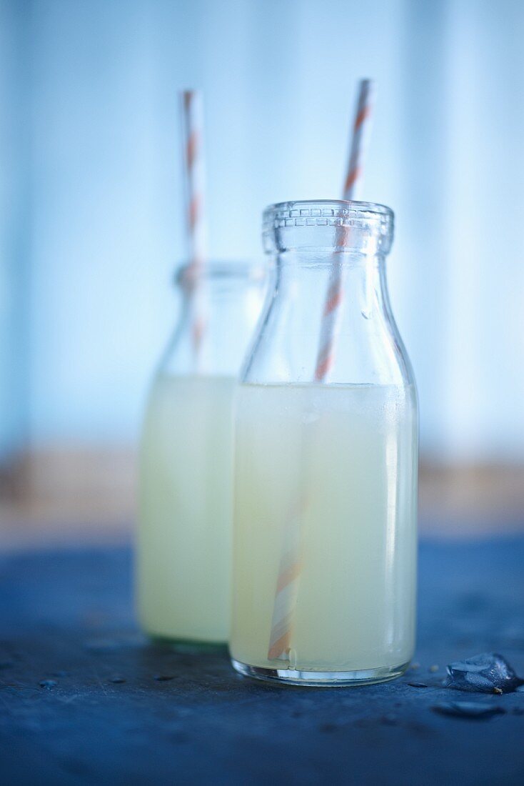 Zwei kleine Limonadenflaschen mit Strohhalm