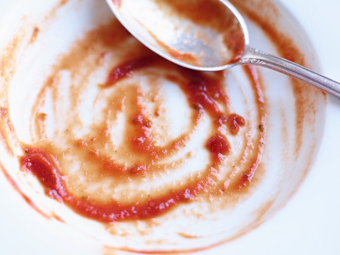 Remains of tomato soup in a bowl with a spoon