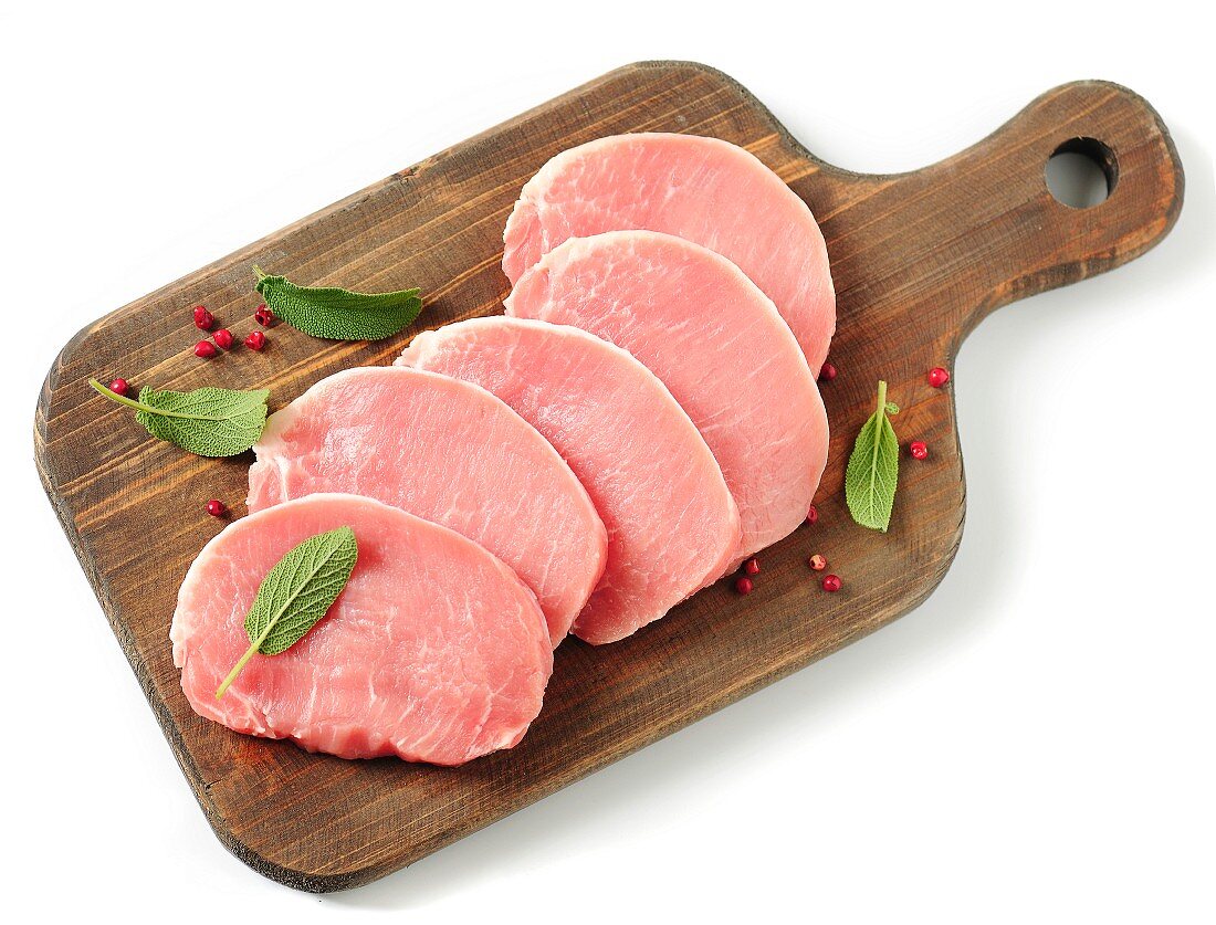 Raw pork minute steaks on a chopping board