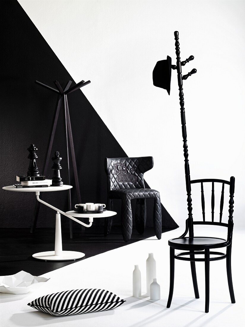 Chair artistically modified into coat stand and white side table against wall with black and white 3D effect