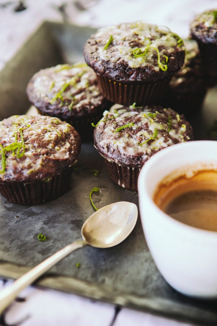 Chocolate muffins decorated with icing sugar and lime zest and served with an espresso