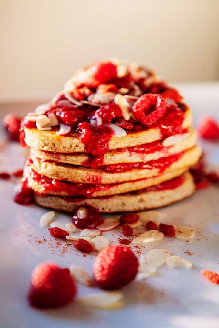 A stack of pancakes with raspberries and slivered almonds