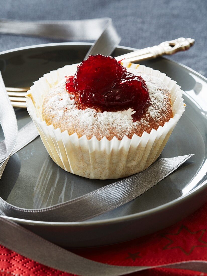 A cupcake topped with cranberry jam and icing sugar