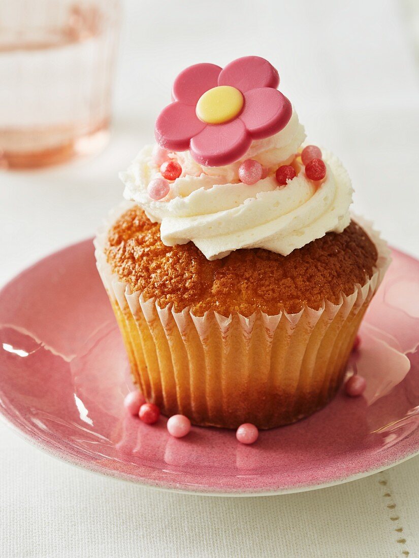 A cupcake decorated with buttercream and a sugar flower