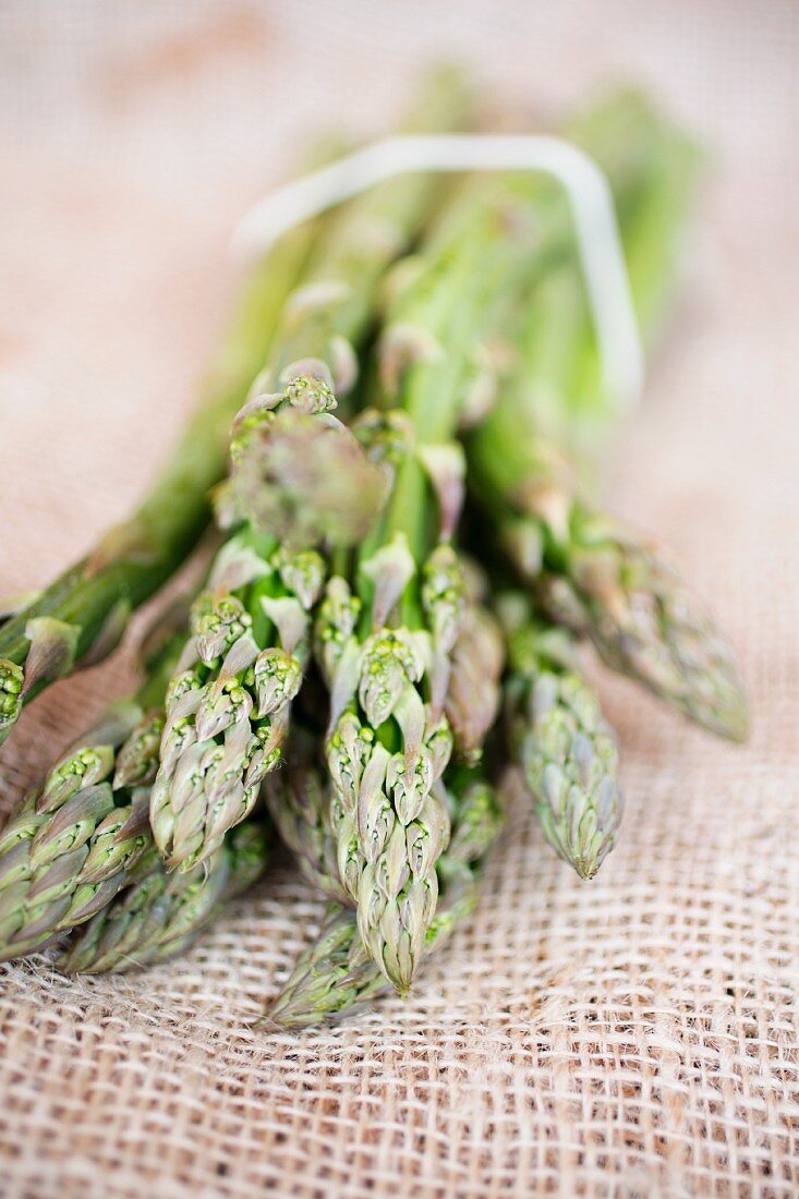 A bunch of green asparagus on a piece of jute