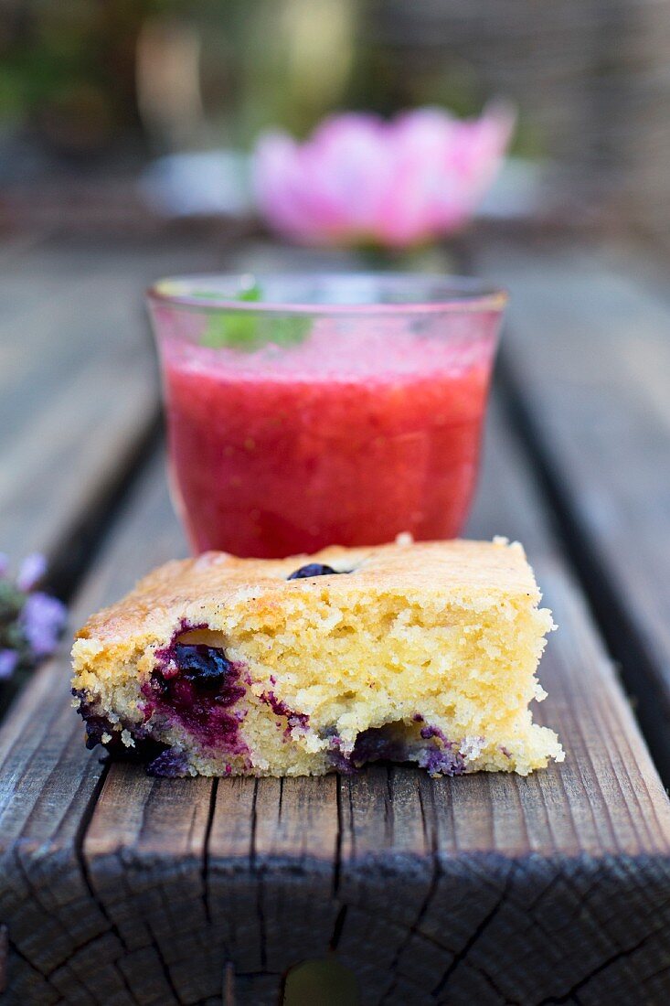 Ein Stück Beerenkuchen und Erdbeerdrink auf Holztisch