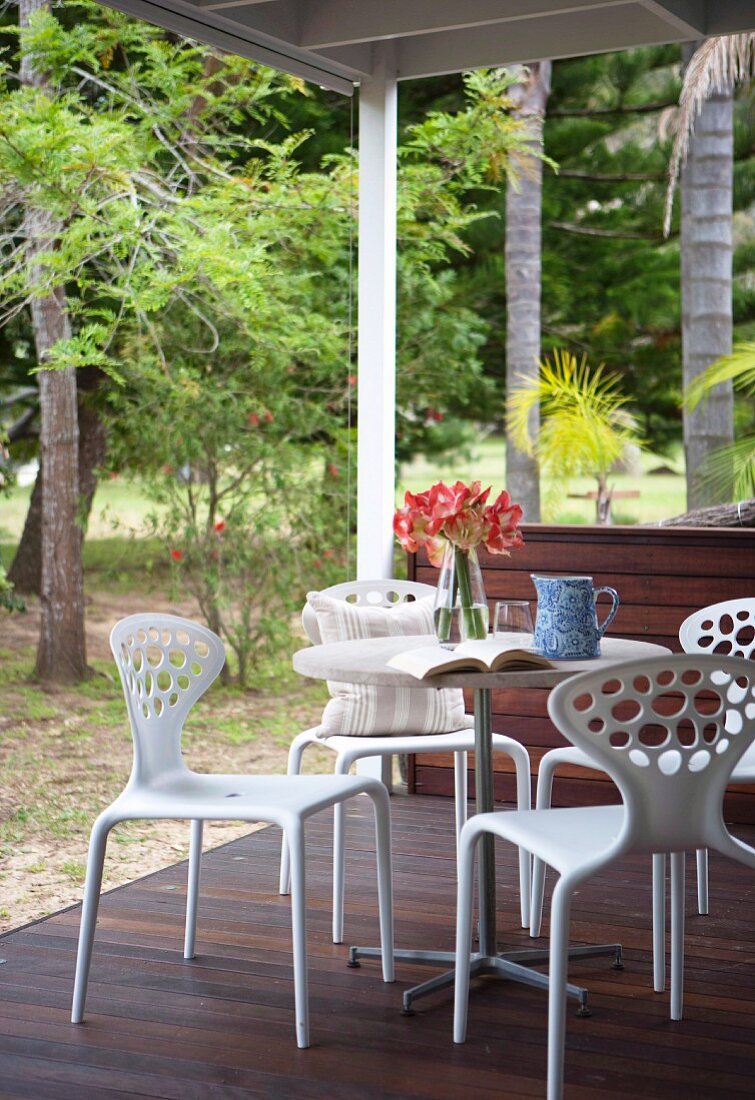 White, designer outdoor furniture on wooden terrace of weekend house in forest