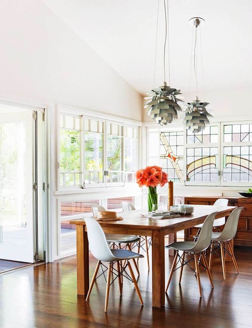 Bauhaus shell chairs around wooden table below Poulsen pendant lamps in rustic atmosphere