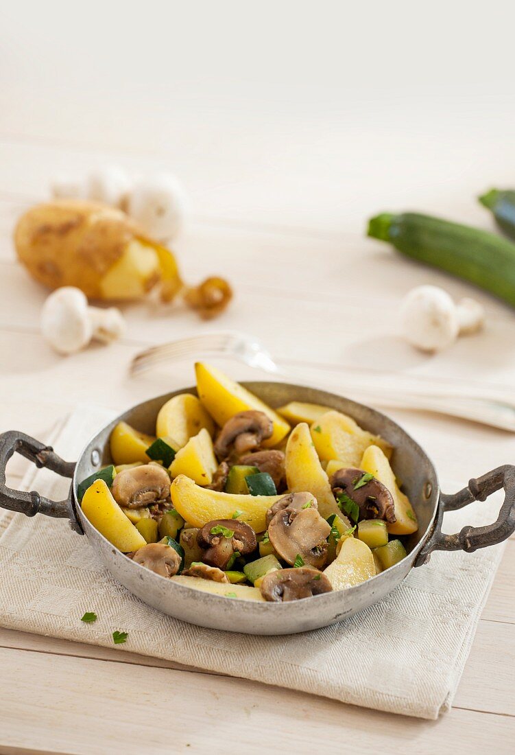 Kartoffeln mit Zucchini und Champignons in einer Pfanne