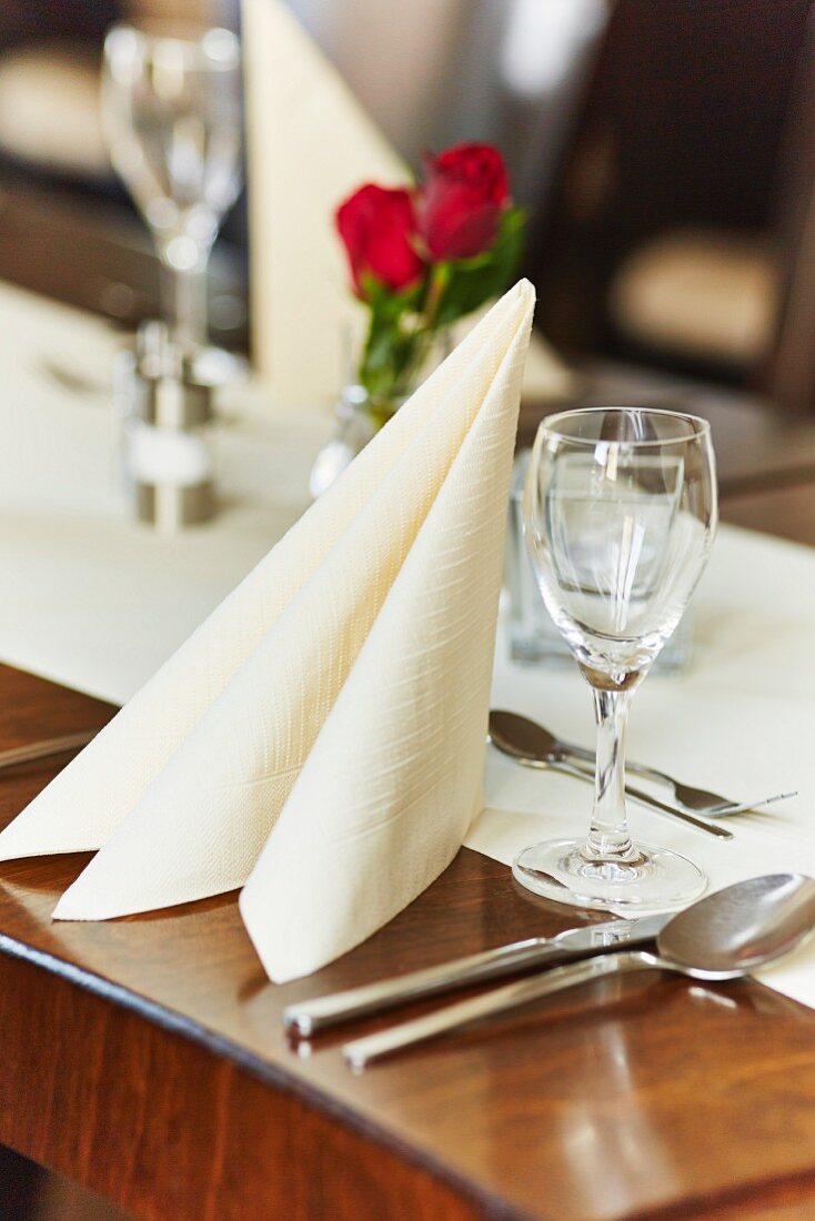 A place setting with a napkin, a glass and cutlery in a restaurant