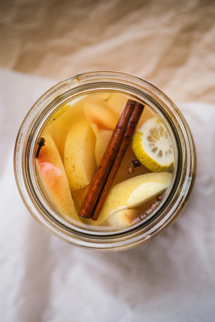 Apple compote with a cinnamon stick, lemon and cloves in a glass jar