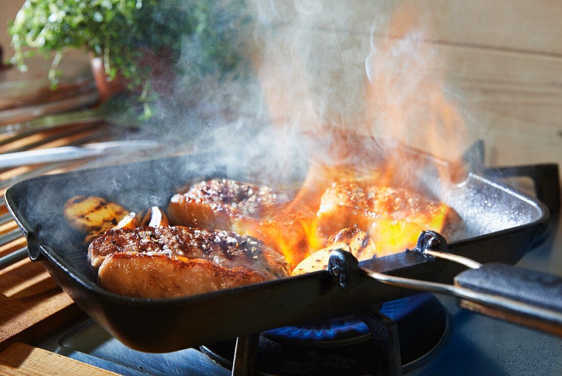 A rump steak being fried in a pan on the hob