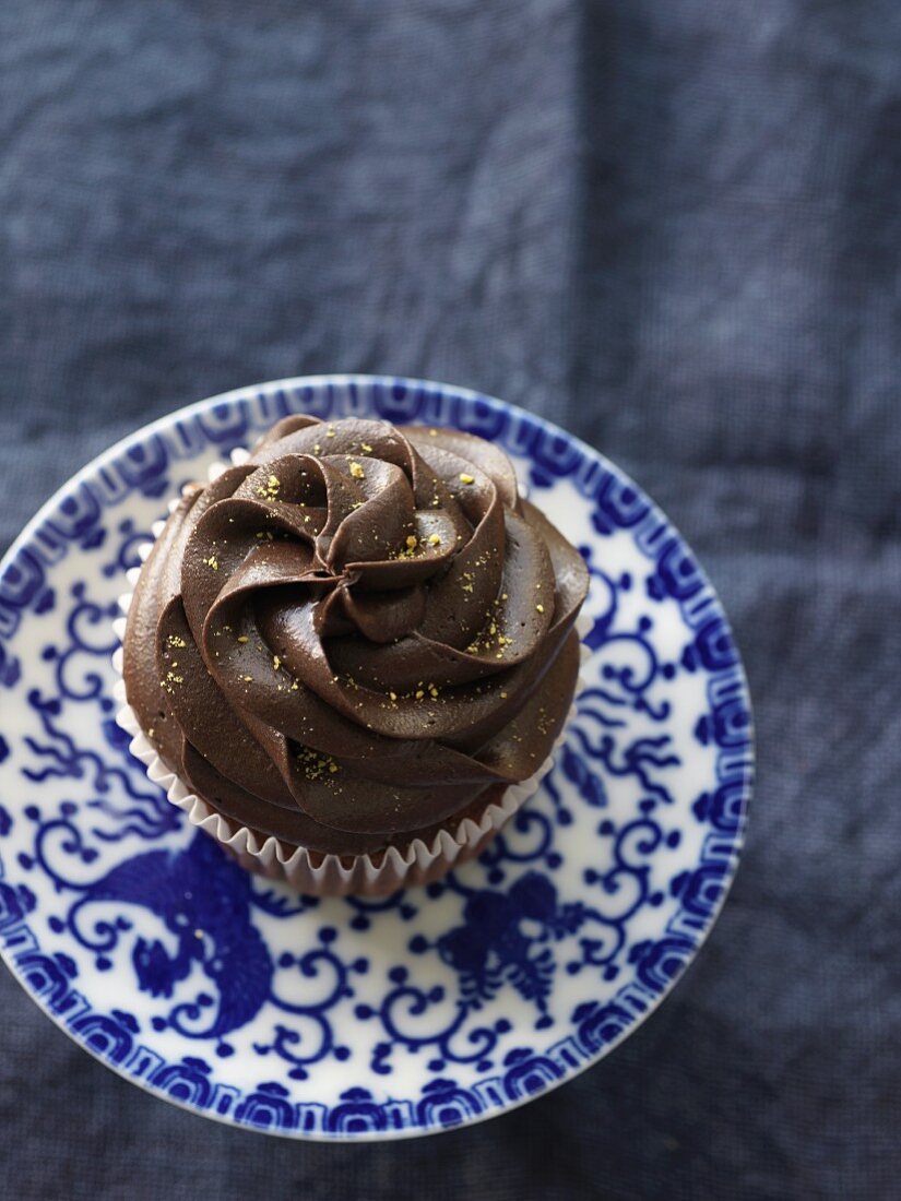 Schokoladen-Cupcake auf blau-weißem Unterteller