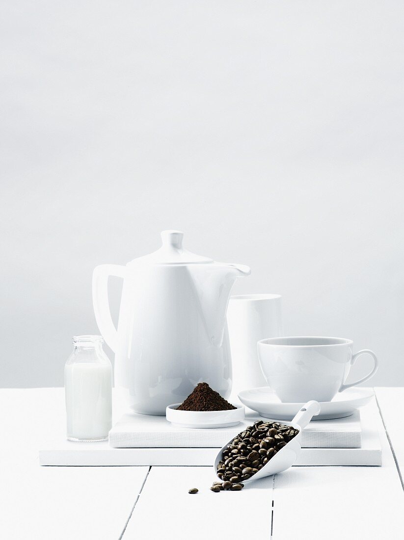 An arrangement of coffee beans, ground coffee and coffee crockery