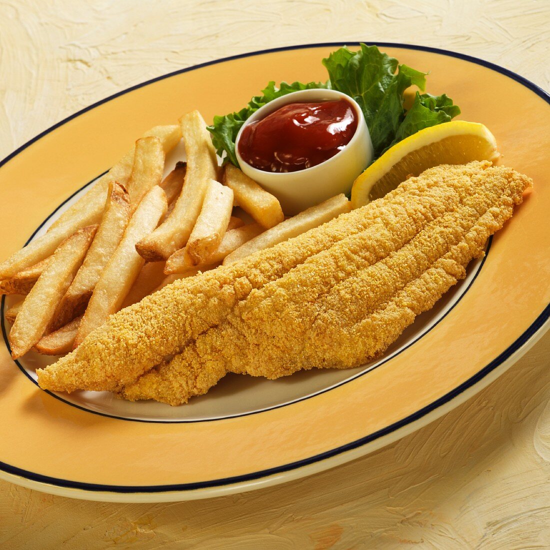 Catfish with a cornflour coating served with fries, lemon and ketchup
