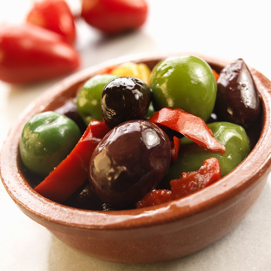 Marinated olives and peppers in a terracotta dish