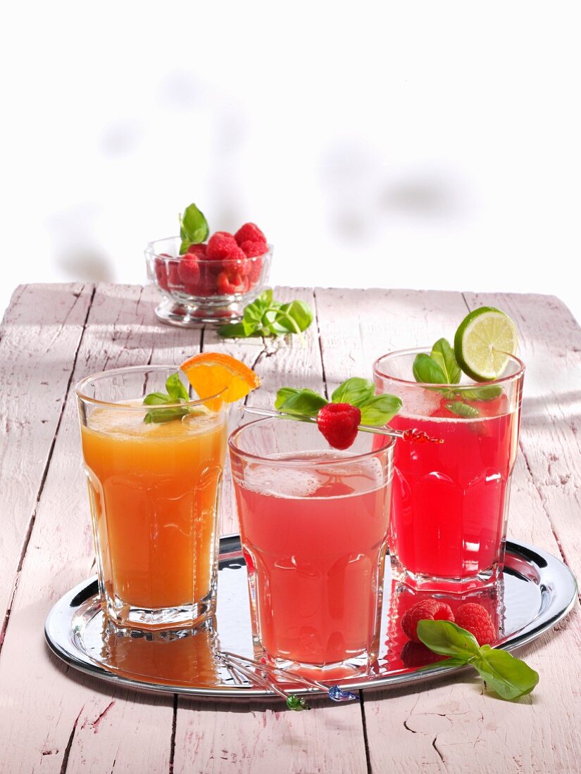 Three different glasses of lemonade (orange & raspberry, ginger & raspberry, and raspberry)