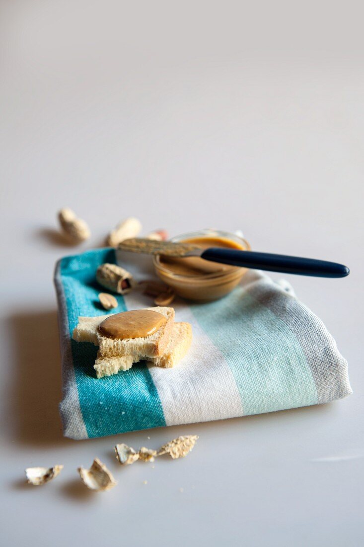 Toast with peanut butter on a tea towel with peanuts