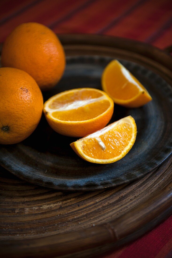 Oranges, whole and sliced, on a plate