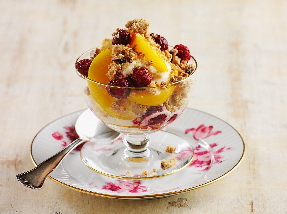 A dessert with yogurt, peaches, raspberries and crunchy muesli